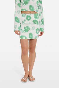 Ensemble composé d'un crop top blanc et d'une jupe avec un motif floral vert ; tissu léger et texturé avec une silhouette ajustée et une fente sur le côté de la jupe.
