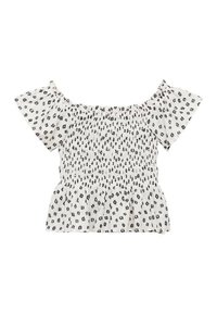 Top bianco off-the-shoulder con stampa nera a pois, corpetto arricciato e maniche corte a volant. Tessuto leggero con una texture morbida.