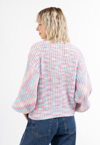 Pastellfarbener gestrickter Pullover mit lockerer Passform, weiten Ärmeln und strukturiertem Stoff. Die Rückansicht zeigt eine Mischung aus rosa, blau und weißen Mustern.