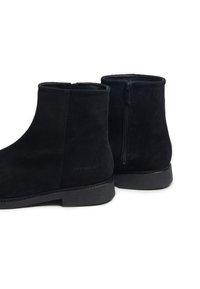 Bottines en daim noir au fini lisse, dotées d'une fermeture éclair sur le côté, d'un talon bas empilé et du nom de la marque embossé sur le côté extérieur.
