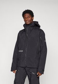 Casaco preto à prova d'água com capuz ajustável, múltiplos bolsos com zíper e punhos reforçados. Teclado durável com acabamento mate.