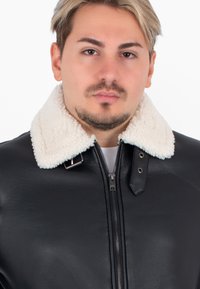 Giubbotto in pelle nera con colletto in finta pelliccia color crema, dotato di chiusura con zip frontale e bottoni laterali per una vestibilità regolabile.