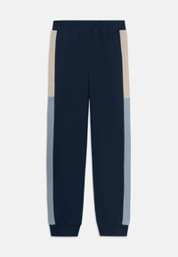 Pantalons de jogging bleu marine avec des panneaux de couleur beige et bleu clair sur les côtés, taille élastique et chevilles resserrées.