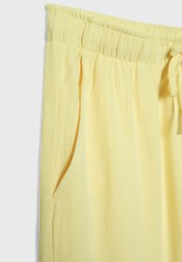 Pantalon à taille élastique jaune avec un tissu texturé, doté de poches latérales et d'une coupe décontractée.