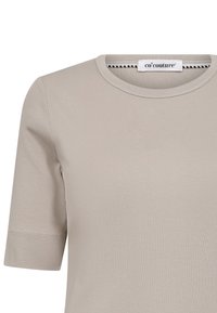 Heledane hallide puuvillane T-särk, millel on ümmargune kaelus ja lühikesed varrukad. Omab puhtaid õmblusi ja sildiga, millel on "co'couture" bränd.