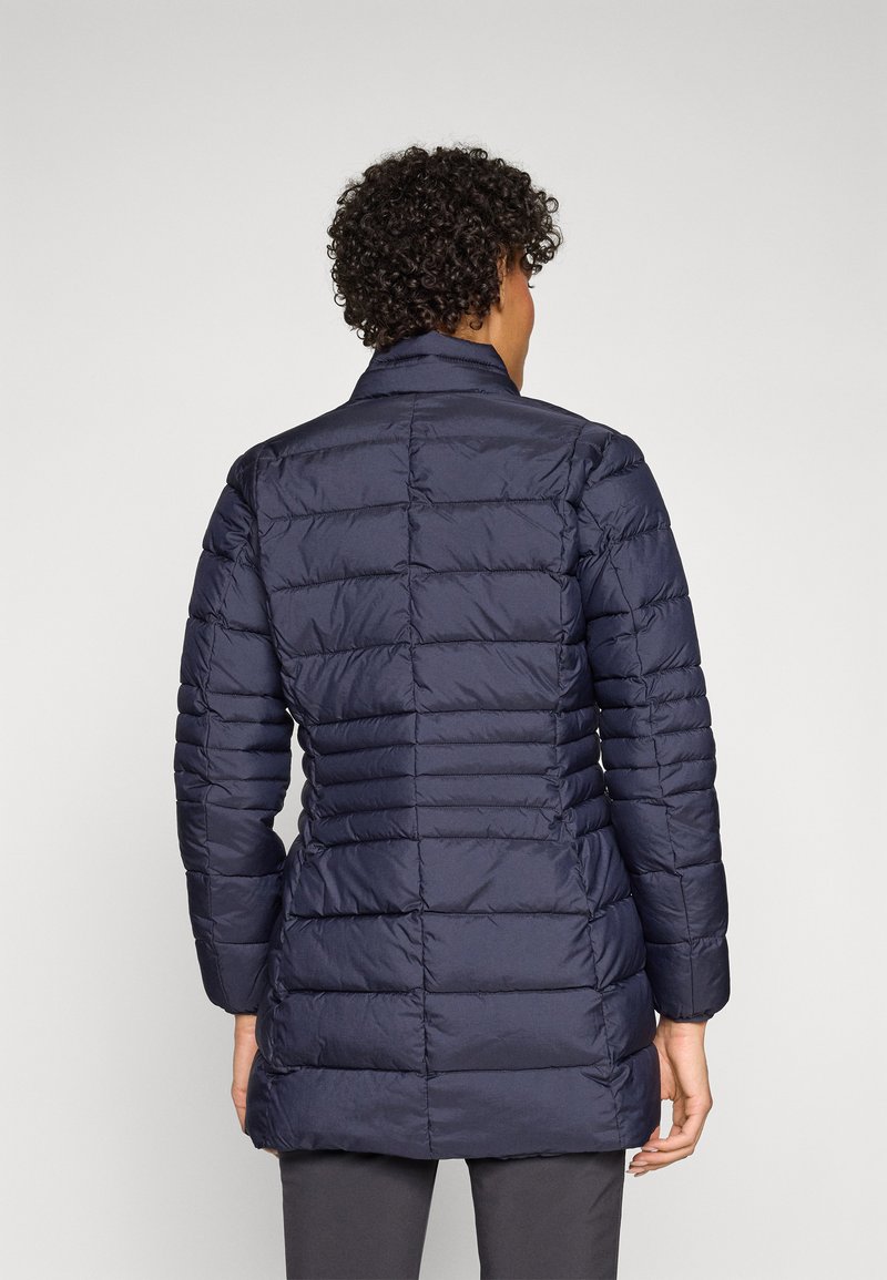Cappotto imbottito blu navy con colletto alto, caratterizzato da cuciture verticali e un retro leggermente più lungo. Realizzato in tessuto leggero e liscio.