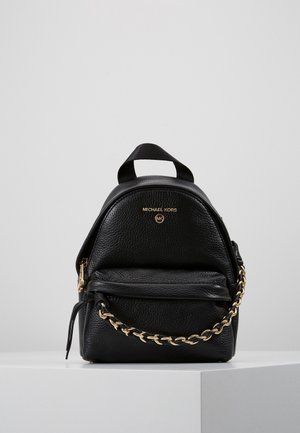 Black pebbled leather mini backpack with front pocket, gold chain detail, top handle, and Michael Kors logo on a plain light background.