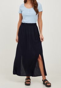Blå ribbet kortærmet top med scoop-neck, parret med en navy maxi-nederdel med smockede linning og slid i siden. Sorte sandaler synlige.