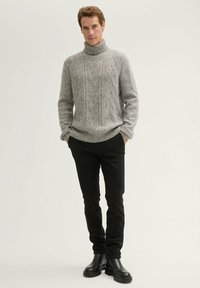 Grauer gestrickter Rollkragenpullover mit einem strukturierten Zopfmuster, kombiniert mit schwarzen Slim-Fit-Hosen und schwarzen Ankle Boots.