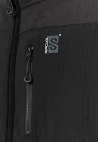 Chaqueta de forro polar negra con un bolsillo con cremallera y detalle de logo. Textura suave con diseño de paneles en contraste, que incluye un cuello alto.