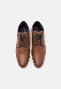 Scarpe in pelle marrone con punte tonde, accenti testurizzati e lacci blu navy. Presentano un design cucito e una finitura liscia e lucida.