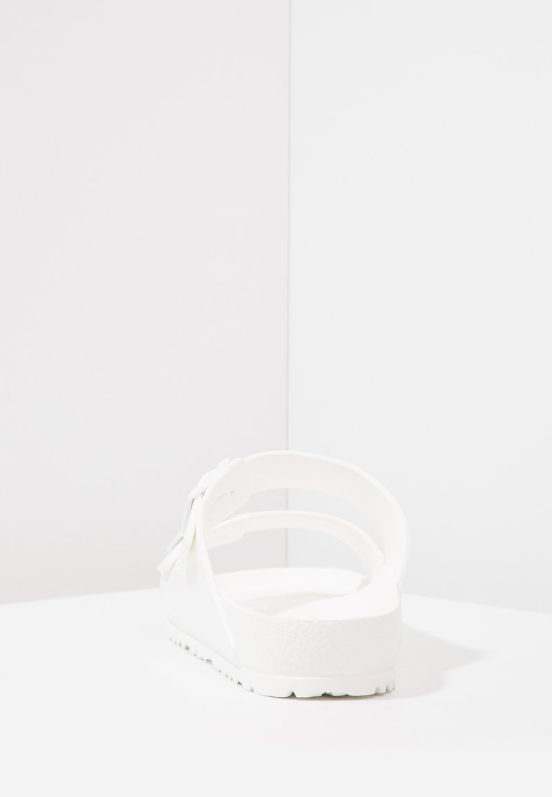 Sandalo bianco con suola piatta, materiale a trama morbida e design con cinturino regolabile. Stile minimalista, senza hardware o motivi visibili.