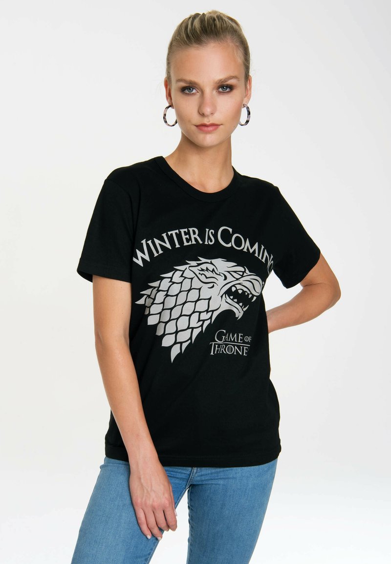 Black cotton t-shirt with a silver "Winter is Coming" text and wolf graphic. Short sleeves, crew neck, and casual fit.