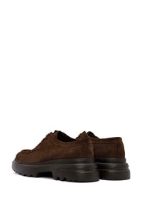 Scarpe in suede marrone con una suola spessa e testurizzata. Presentano una forma arrotondata, un design con lacci e dettagli di cucitura sottili sulla parte superiore.