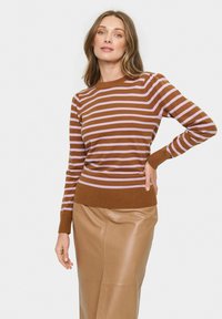 Gestreifter Pullover in Braun und Lavendel mit Rundhalsausschnitt und gerippten Bündchen, kombiniert mit einem rock aus braunem Leder. Glatte Textur, enganliegendes Design.