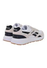 Weiße und beige Wildleder- und Mesh-Sneaker mit schwarzen Akzenten, ausgestattet mit gepolstertem Kragen, Gummisohle und Reebok-Logo.