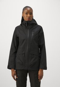Veste noire imperméable avec zip sur le devant, capuche réglable et deux poches avant. Présente une texture extérieure lisse et un design ajusté.
