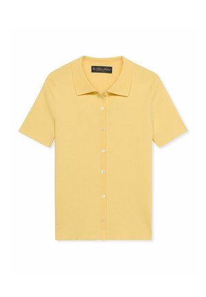Polo gialla a maniche corte con bottoni e colletto, distesa su uno sfondo bianco.