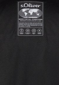s.Oliver apģērbu etiķete uz melnas auduma ar pasaules karti, produkta īpašībām un priekšrocībām dažādiem apstākļiem un lietojumiem.