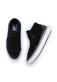 Černé kotníkové tenisky z semiše s bílými gumovými podrážkami, černými detaily a kontrastním prošitím. Mají ploché tkaničky a štítek s logem.