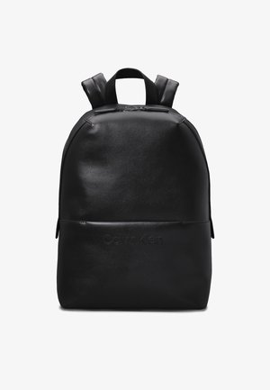 Zaino in pelle nera con forma arrotondata, dotato di spallacci regolabili e tasca con zip frontale. "Calvin Klein" impresso sul davanti.