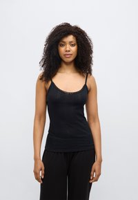 Μαύρη φανέλα με λεπτές τιράντες, με υφή σχεδίου και δαντέλα κατά μήκος του μπούστου. Συνδυάζεται με φαρδιά μαύρη παντελόνα.