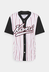Maglietta da baseball bianca con strisce verticali rosse e maniche nere. Presenta una chiusura a bottoni davanti e il logo "Kani" in corsivo, contornato di nero.