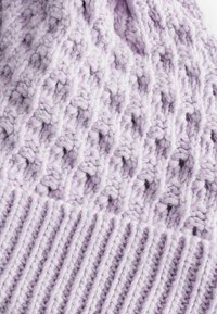 Bonnet en maille lavande avec un design texturé en mailles ouvertes et un bord côtelé, mettant en valeur un fil doux et un look léger.