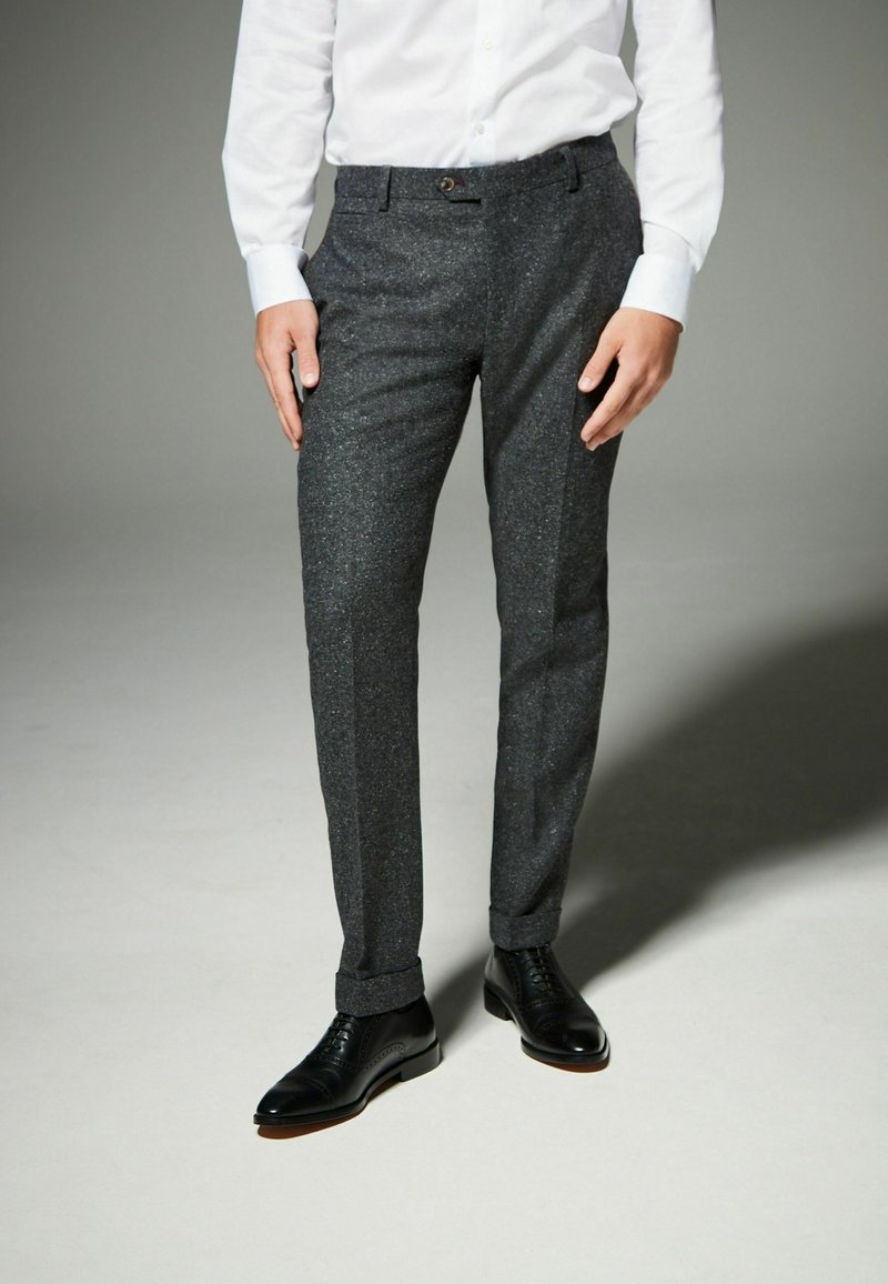 Gray tailored trousers with a textured fabric, front pockets, and a single button closure. Paired with black dress shoes.