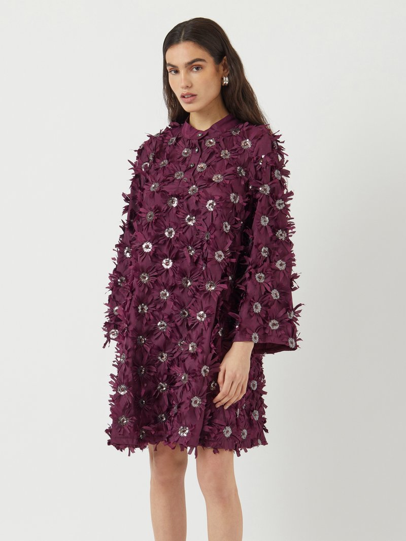 Vibrant lilla kjole med blomsterapplikasjoner, paljettdetaljer, krage med knapper og lange ermer, med et teksturert stoffdesign.