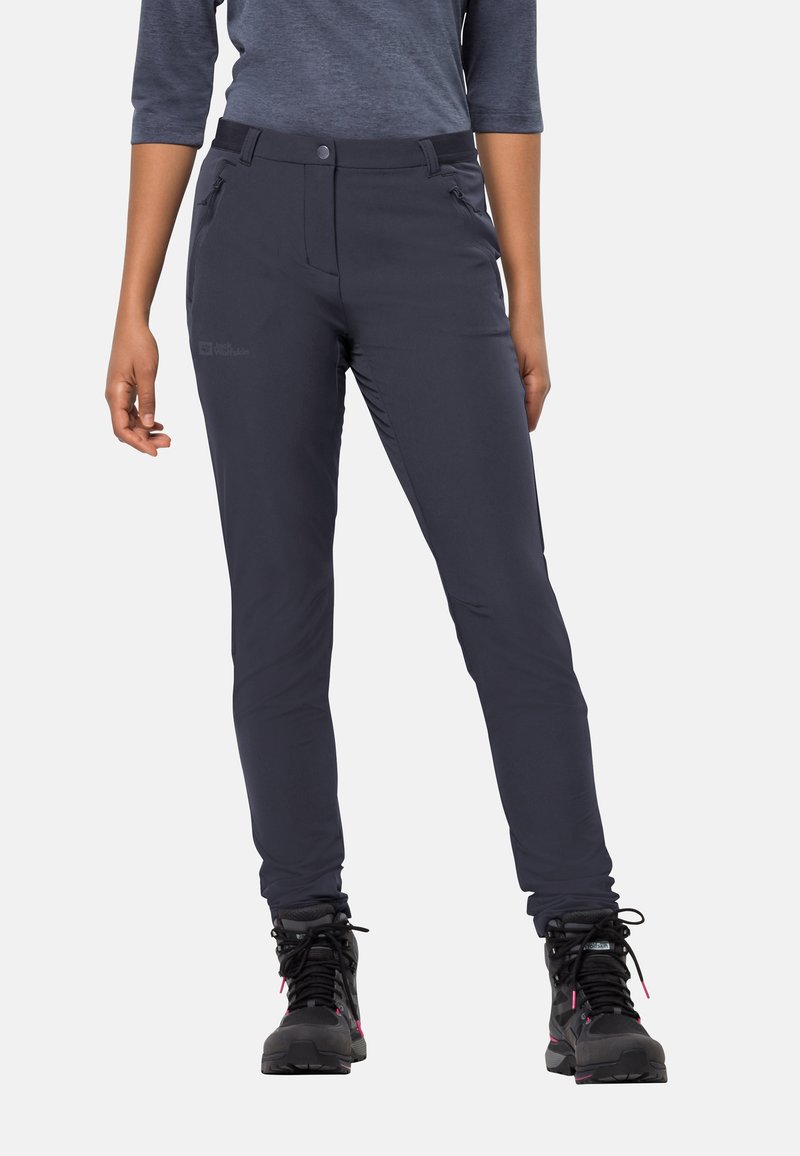 Pantaloni da outdoor in tessuto elastico nero con vestibilità slim. Presentano tasche laterali e chiusura con bottone. Indossati con stivali da escursione neri.