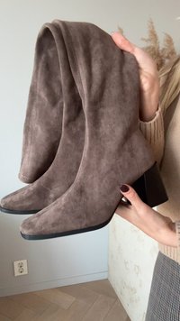 Pruunist suede'ist pahkluu saapad, millel on terav nina, plokksiin ja volditud ülemine osa. Tekstuur on pehme ning disain sisaldab minimaalseid õmblusdetailide.