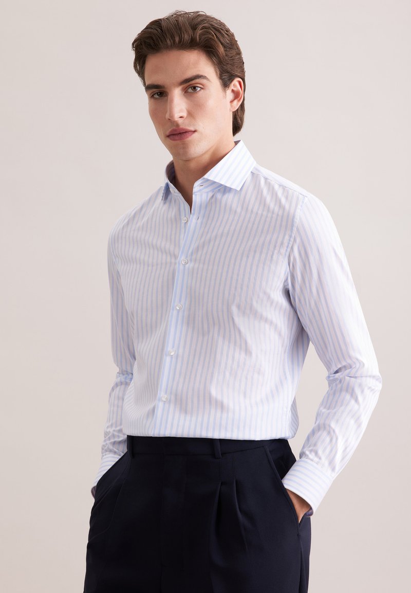 Jasnoniebieska i biała koszula w paski z długim rękawem, z kołnierzem w szpic, zapinana na guziki z przodu oraz standardowymi mankietami, w zestawieniu z ciemnogranatowymi spodniami.