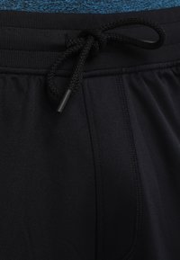 Black athletic shorts featuring an elastic waistband with a black drawstring and visible stitching detail. Soft, smooth fabric texture.