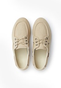 Scarpe in tela beige con punta rotonda, design con lacci, occhielli in metallo e tessuto strutturato. L'interno presenta una fodera liscia.