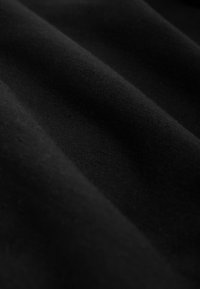 Glatter schwarzer Stoff mit weichen Falten und feiner Textur bei gleichmäßiger Beleuchtung.