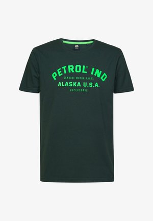 Camiseta de algodón verde oscuro con mangas cortas y cuello redondo. Presenta un texto en verde brillante y en negrita: "PETROL IND ALASKA U.S.A. SUPersonic."