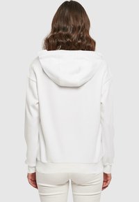 Felpa bianca con una vestibilità rilassata, tessuto testurizzato e cappuccio. Design semplice con polsini e orlo a costine, dotata di tasca a marsupio.