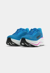 Baskets de sport bleues avec une tige en mesh, semelle rembourrée et semelle extérieure noire avec des accents blancs et roses. Logo sur le côté.