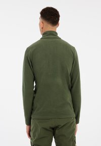 Groene, langmouwige pullover gemaakt van textuurstof, met een hoge kraag en een aansluitend ontwerp, gecombineerd met bijpassende groene broek.