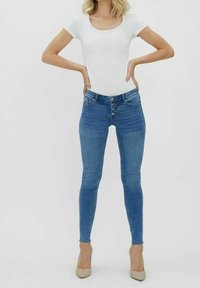 Fitted blue denim jeans with a high waist, five-pocket design, and front button closure, paired with a white short-sleeve top.
