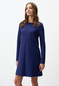 Abito a maniche lunghe blu navy realizzato in un tessuto liscio, presenta un colletto rotondo e un'orlo svasato, con una singola cucitura sul davanti.