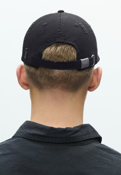 Μαύρο βαμβακερό καπέλο μπέιζμπολ με ρυθμιζόμενο λουράκι, διαθέτει ανάγλυφο λογότυπο στο πίσω μέρος και λεπτομέρειες με ραφές. Εμφανίζεται η πίσω όψη.