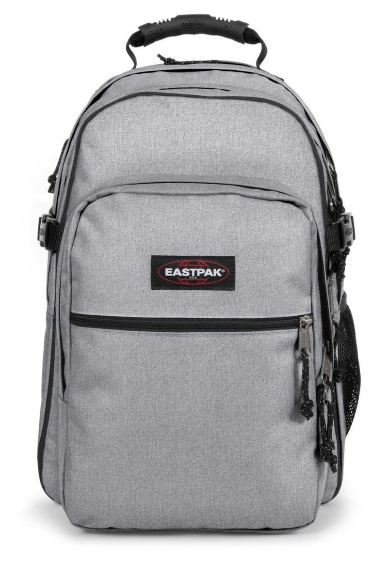 Grå Eastpak ryggsäck, tillverkad av vävt tyg, har en framficka med dragkedja, sidoficka i nät och vadderade axelremmar för komfort.