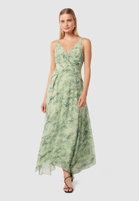 Long green dress with a v-neck and thin straps, made of lightweight fabric featuring a marbled pattern. Side slit for added movement.
