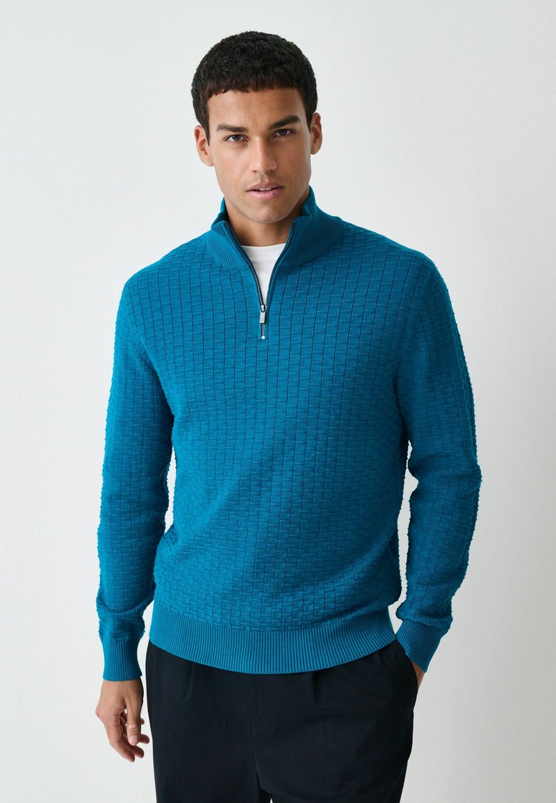 Tannengrüner, strukturierter Pullover mit einem Viertel-Reißverschluss-Kragen sowie gerippten Bündchen und Saum. Verfügt über ein geometrisches Muster im gesamten Stoff.