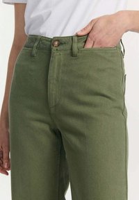 Olijfgroene hoge taille broek gemaakt van stevig materiaal, met een knoopsluiting, zijzakken en een rechte pijpenontwerp.