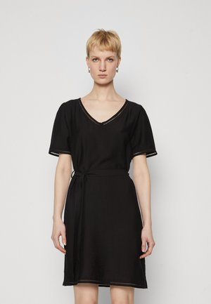 Rochie neagră cu decolteu în V, mâneci scurte cu volane și talie legată. Oferă detalii din dantelă la marginea mânecilor și un material moale, texturat.