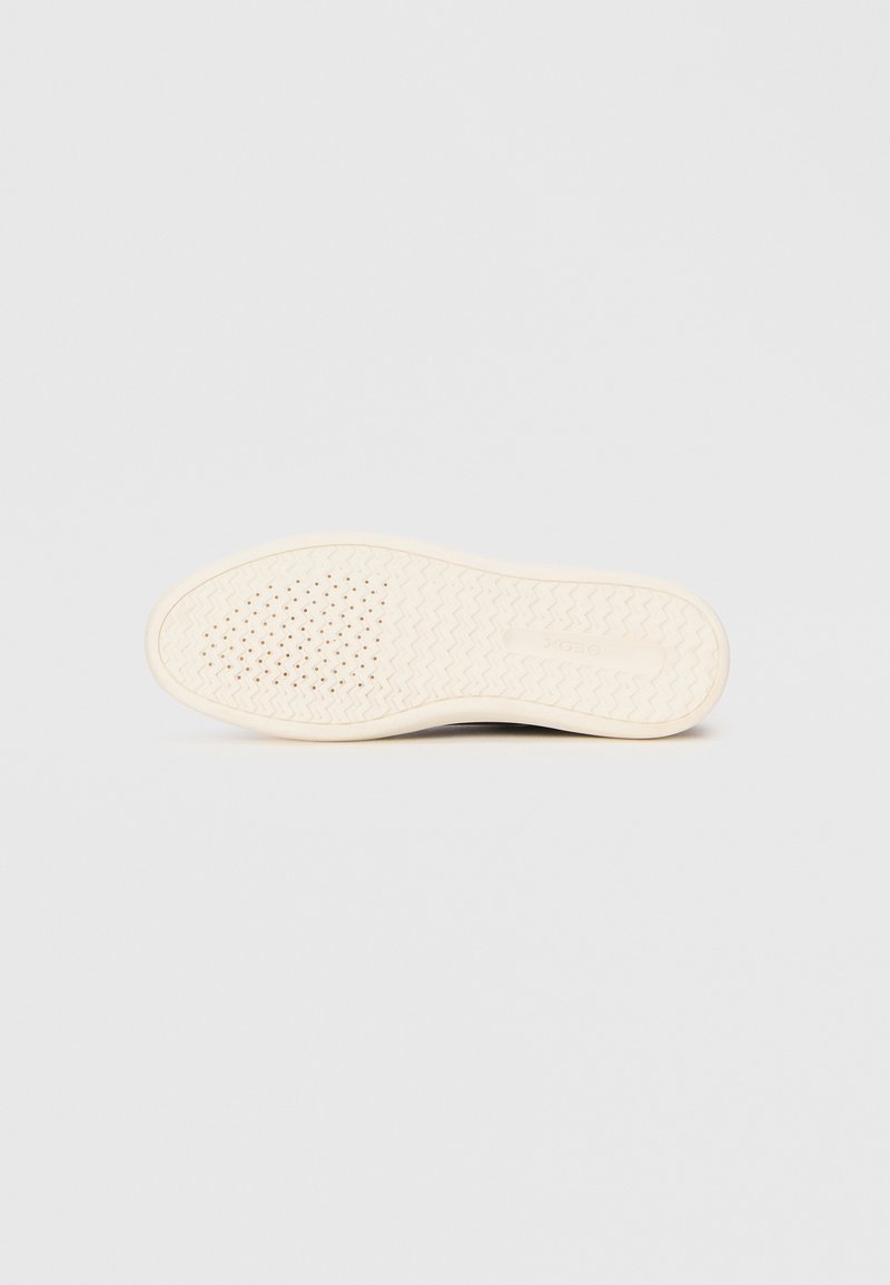 Semelle de sneaker avec une surface texturée en caoutchouc de couleur blanc cassé. Présente un design à motifs et de petites perforations pour une meilleure adhérence et flexibilité.