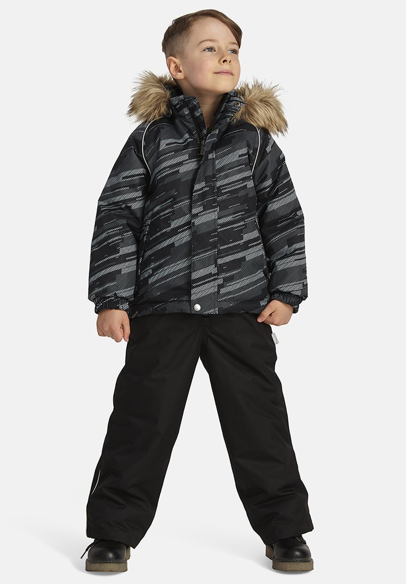 Mustaga ja halli mustriga soojustatud jakk karusnaha voodriga kapuutsiga, koos mustade lumepükste ja tugeva musta jalanõudega.